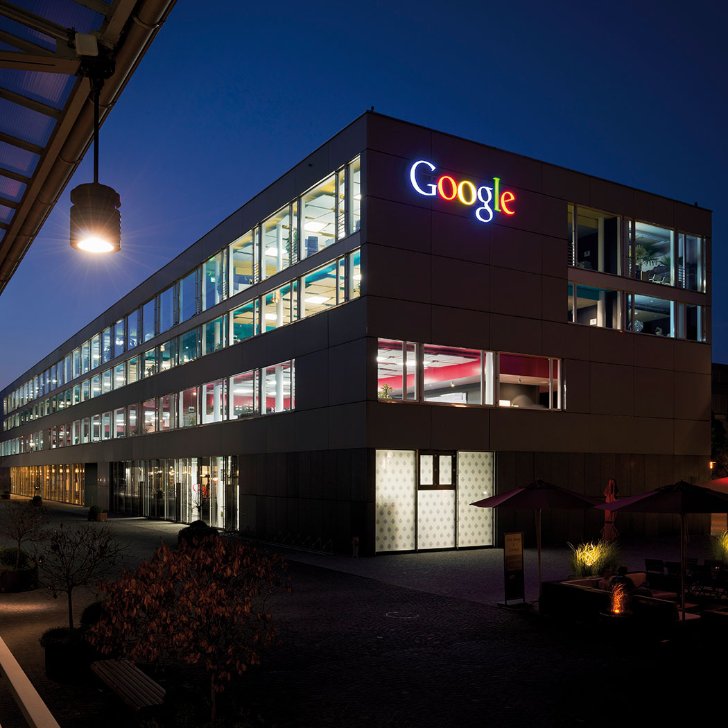 Exterior of Google office building at night with lighted logo sign, Google Cloud in banking | DXC Technology 
