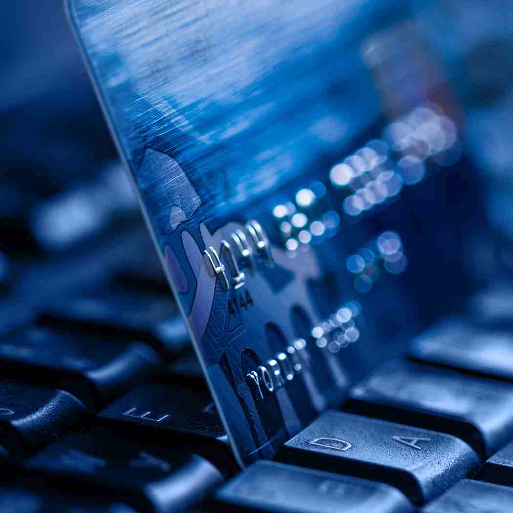 Credit card tucked between rows of laptop keyboard, Banking Software Applications | DXC Technology