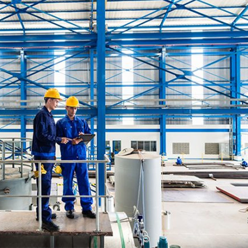 Workers wearing hard hats reviewing information on tablet on plant floor, Private Cloud | DXC Technology