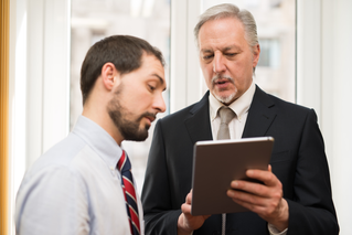 Two men studying information on a tablet, Network Consulting & Advisory | DXC Technology