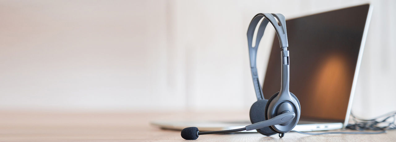 Communication support, call center and customer service help desk. VOIP headset on telephone keyboard.