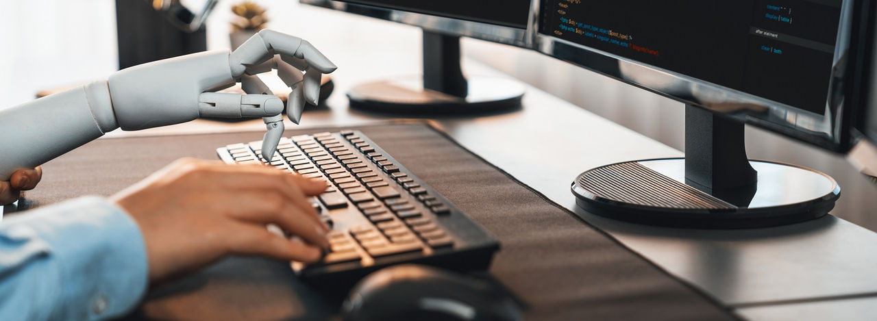 Program coding automation by generative artificial intelligence or AI concept. Collaboration between robotic hand and human software developer solving, debugging or writing script.Trailblazing