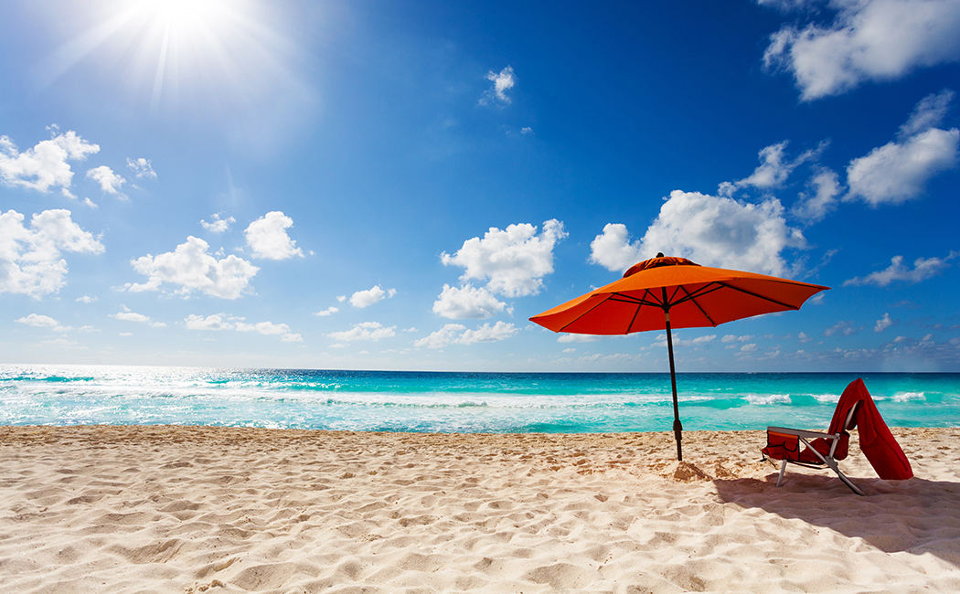 orange beach umbrella and chair at ocean edge