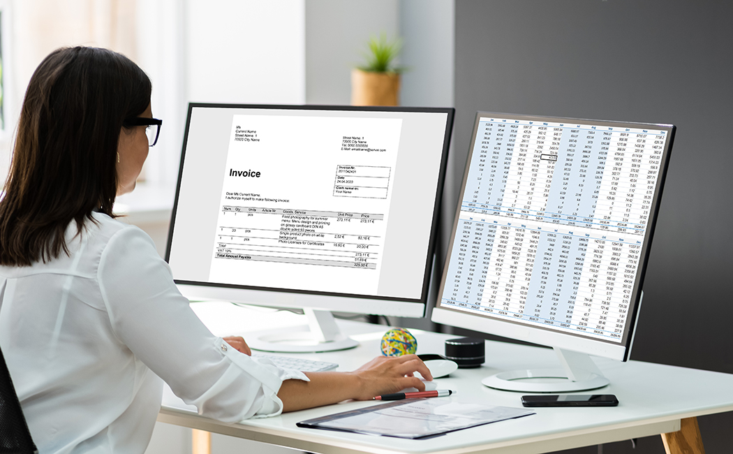 woman looking at finances on two monitors