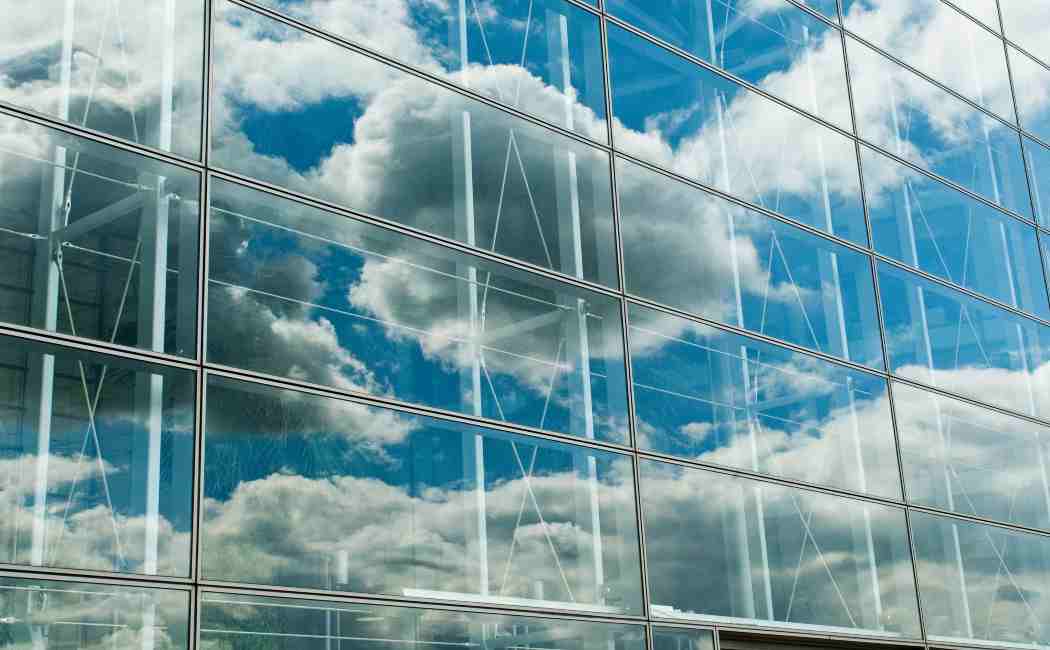 cloud images reflected on building glass, AWS | DXC Technology