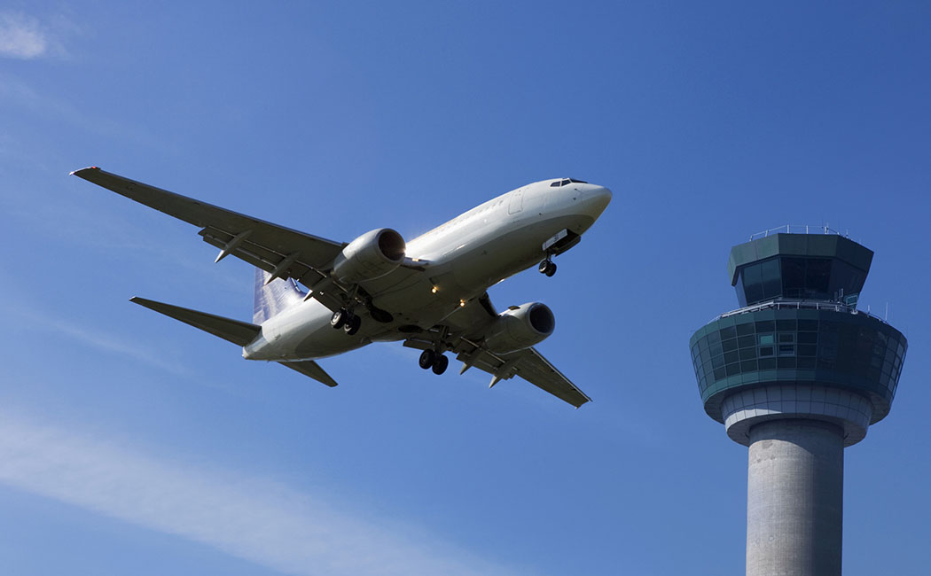 Plane flying past control tower --- Image by © Nick Dolding/cultura/Corbis